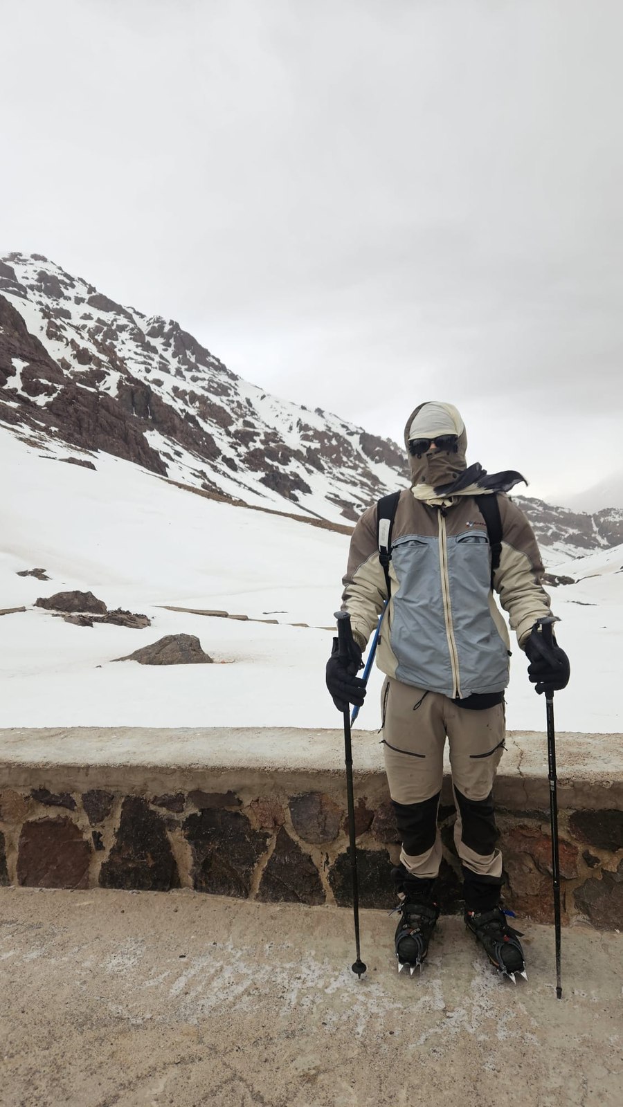 Mountaineering in snow gear with trekking poles